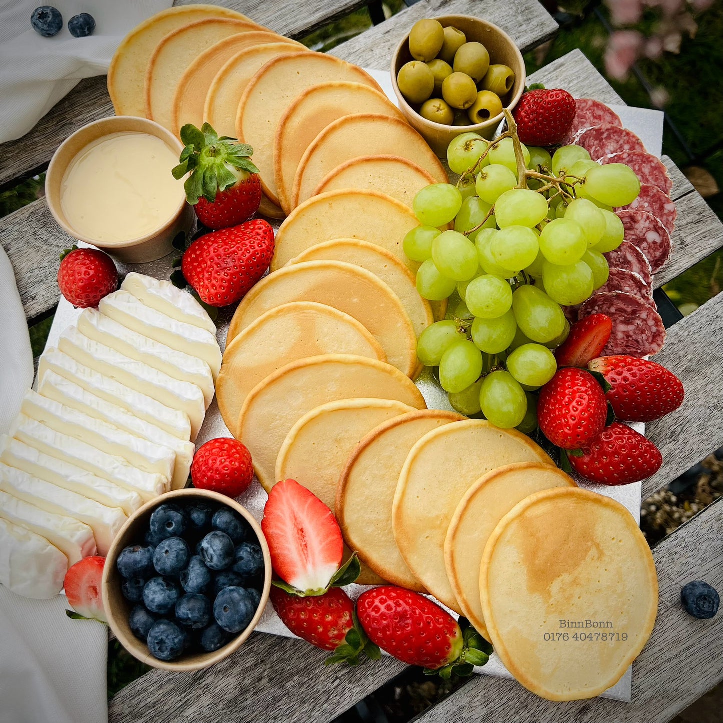 Pancake-Board mit Käse Salami Oliven und verschiedenen Früchten